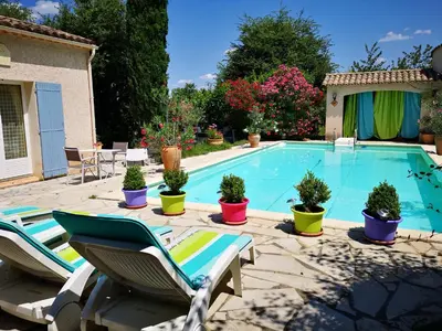 a swimming pool with two lawn chairs and potted plants at Chambre d'hôte à Pierrevert, en Haute Provence in Pierrevert
