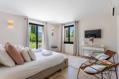 a white bedroom with a large bed and a tv at Villa Kiki 4 chambres Climatisée Ménerbes in Ménerbes