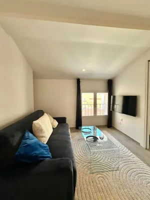 a living room with a black couch and a table at Charmant T2 à deux pas du cours Mirabeau in Aix-en-Provence