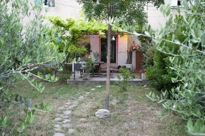 a garden with a small tree in front of a house at Maison dans un coin de verdure proche de la Sorgue in LʼIsle-sur-la-Sorgue