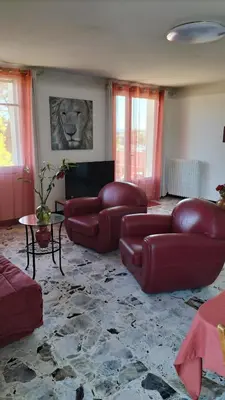 a living room with red leather couches and a table at Escale vélo La petite Reine in Cavaillon
