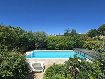 a swimming pool with two lawn chairs and trees at Cocoon Luberon in Lauris
