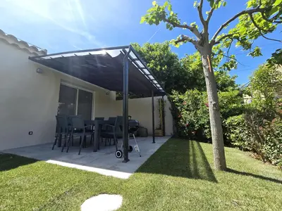 a patio with a solarium with a table and a tree at Cocoon Luberon in Lauris
