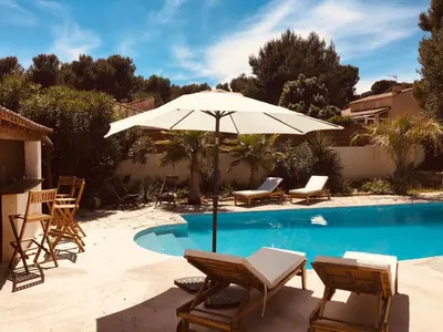 a pool with chairs and an umbrella and a table and chairs at Provencal villa with pool and large terrace in Rognac