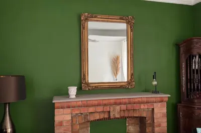 a mirror over a fireplace in a green room at Elivi Elegant Art Deco house with Garden Walk to the Heart of Town in LʼIsle-sur-la-Sorgue