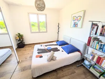a bedroom with a large white bed with blue pillows at Villa haut de gamme avec piscine et grand jardin in Aix-en-Provence