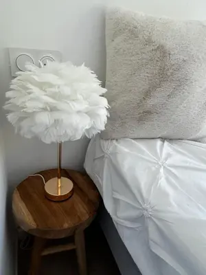 a lamp on a wooden table next to a bed at L'Essentiel Room in Velaux