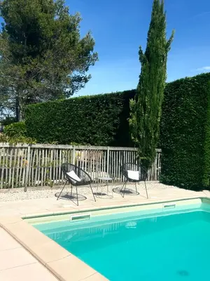 a pool with two chairs and a table next to a fence at Chambre L in Les Taillades