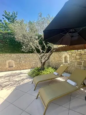 two chairs and an umbrella on a patio at Chambre L in Les Taillades