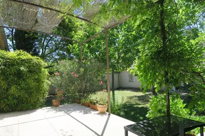 a garden with potted plants and a pergola at L'embellie in Châteaurenard