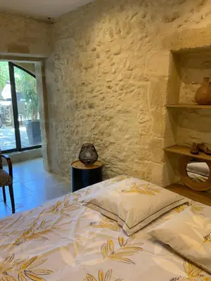 a bedroom with a bed and a stone wall at Maisonnette de charme 60m2 in Robion en Luberon