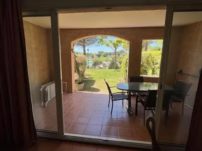 a dining room with a table and chairs and a patio at Appartement de charme sur le domaine de Pont Royal à Mallemort, en rez-de-jardin avec terrasse & piscine et vue sur le Golf in Mallemort