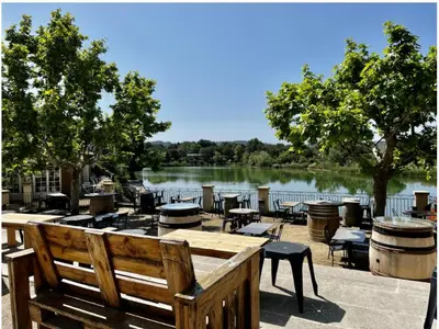 a view of a lake with tables and chairs at Appartement de charme sur le domaine de Pont Royal à Mallemort, en rez-de-jardin avec terrasse & piscine et vue sur le Golf in Mallemort