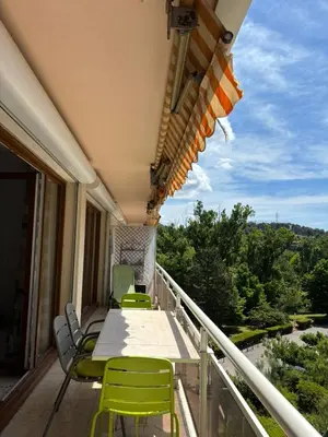 a deck with a table and chairs on a balcony at Aix en Provence, dans grande résidence arborée, appartement de 80m2 in Aix-en-Provence
