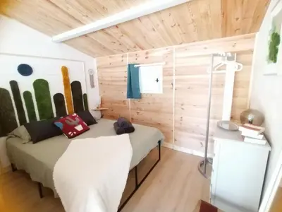 a bedroom with a bed in a room with wooden walls at La Ch'tite Maison in Céreste