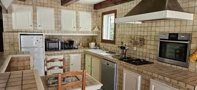 a kitchen with white cabinets and a stove top oven at Villa en Provence avec piscine in Sénas