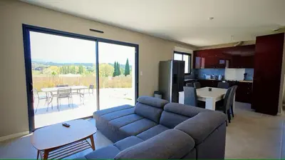 a living room with a blue couch and a kitchen at Cap sur le Ventoux in Mormoiron