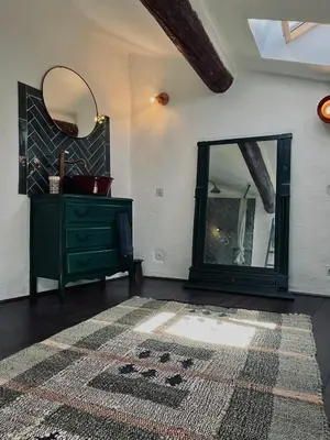 a room with a mirror and a dresser and a rug at La Biscornue in Lauris