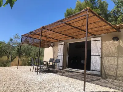 a pavilion with chairs and a table in front of a building at L'olivier in Aureille