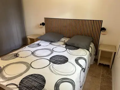 a bed with a black and white comforter and two pillows at L'olivier in Aureille