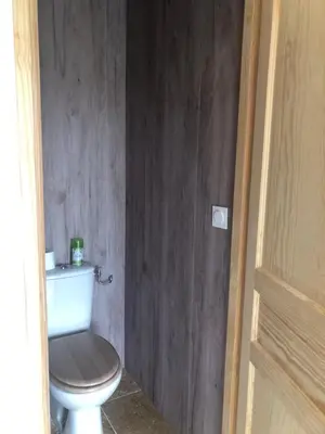 a bathroom with a toilet with a wooden wall at L'olivier in Aureille