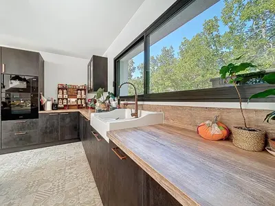 a kitchen with a sink and a large window at La villa dans les arbres - Triangle d'or du Luberon in Ménerbes