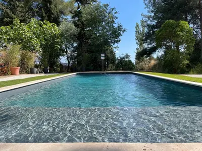 a swimming pool with blue water in a yard at Tiny Aix - Maison Odonata in Aix-en-Provence