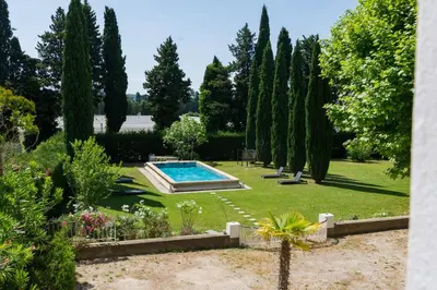 a garden with a swimming pool and trees at Château vert in Cavaillon