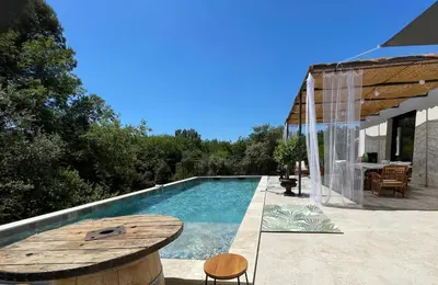 a pool with a table and chairs next to a house at Chambre Deluxe - vue jardin - située dans le triangle d'or du Luberon in Ménerbes