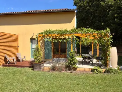 a pergola with a table and chairs in a yard at Au doux paillis Sorgue in Le Thor