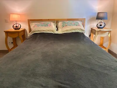 a bedroom with a large bed with two end tables at Au doux paillis Sorgue in Le Thor