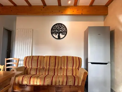 a living room with a couch and a refrigerator at Au doux paillis Sorgue in Le Thor
