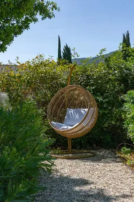a rattan chair sitting in a garden at La Note Bleue Luberon in Maubec