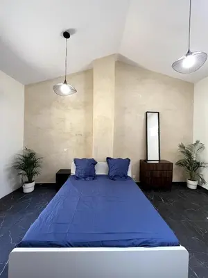a bedroom with a large blue bed with blue pillows at jungle room in La Tour-dʼAigues