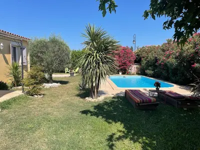 a yard with two benches and a swimming pool at Maison de vacances in Le Thor