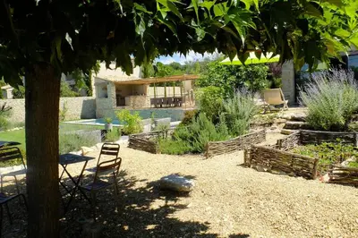 a garden with chairs and a house in the background at La Grande Bergerie in Saint-Saturnin-les-Apt