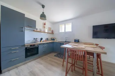 a kitchen with blue cabinets and a table with chairs at Maison proche Avignon Clim Terrasse wifi 4pers in Jonquerettes