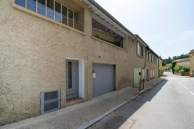 an empty street next to a building with a garage at Maison proche Avignon Clim Terrasse wifi 4pers in Jonquerettes