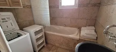 a bathroom with a tub and a sink and a washing machine at Maison conviviale avec jardin à Revest-des-Brousses in Vachères