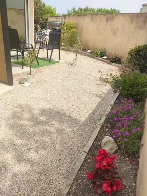 a garden with flowers and a patio with a table at Mayka in LʼIsle-sur-la-Sorgue