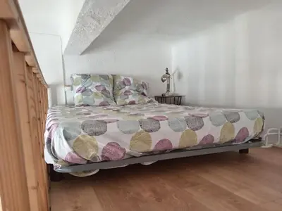 a bed with a comforter and pillows in a bedroom at Charmant studio centre historique Aix in Aix-en-Provence