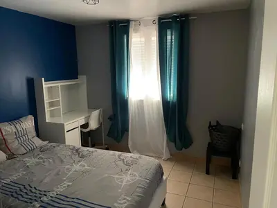 a bedroom with a bed and a window with blue curtains at Villa de caractères,piscine, vue sur le luberon,3 chambres in Cheval-Blanc