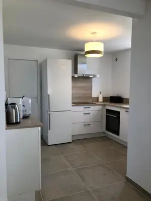 a kitchen with white cabinets and a refrigerator at Gîte 6 pers en Provence avec grande piscine partagée avec 2nd gîte - 6 pers house in Provence with a large swimming pool to be shared with a 2nd house in Cornillon-Confoux