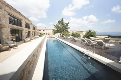 a swimming pool with chairs next to a building at Domaine Château du Bois Provence in Lagarde-dʼApt