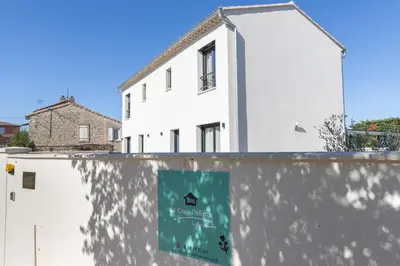 a white house with a sign on a wall at Dolce Vita Piscine in LʼIsle-sur-la-Sorgue