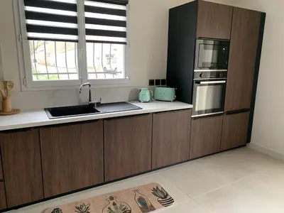 a kitchen with wooden cabinets and a sink and a window at Villa Serena - 3 chambres grand confort - 6 personnes in Carpentras