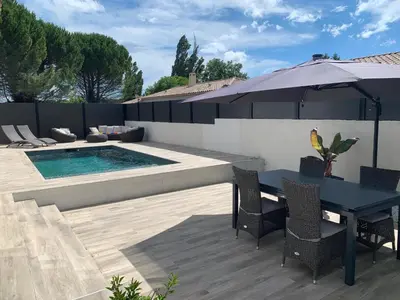 a patio with a table and an umbrella and a pool at Maison agréable pour vacances réussies in Vernègues