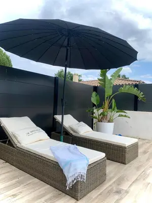 two beds on a balcony with an umbrella at Maison agréable pour vacances réussies in Vernègues