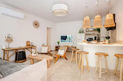a kitchen and living room with wooden stools at La Cour Secrète - Suite Bali Balnéo privé Carpentras in Carpentras