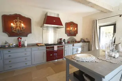 a large kitchen with white cabinets and a table at Mas aux gourmandises in Oppède